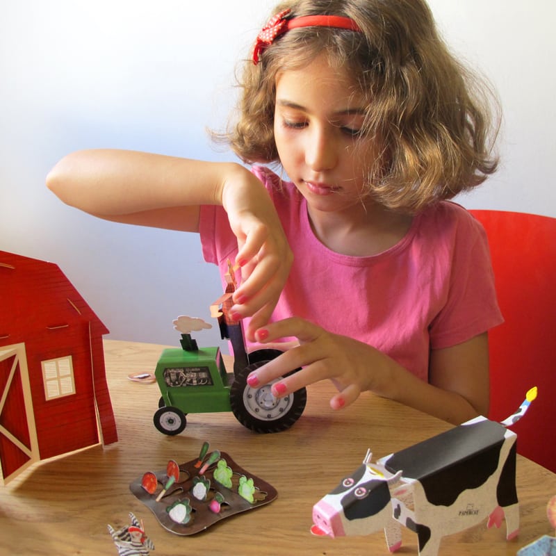ילדה משחקת בצעצועי נייר של ערכת החווה