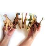 ידיים מחזיקות שרשרת מנייר פתוחה כמו אקורדיון, בדמויות דינוזאורים